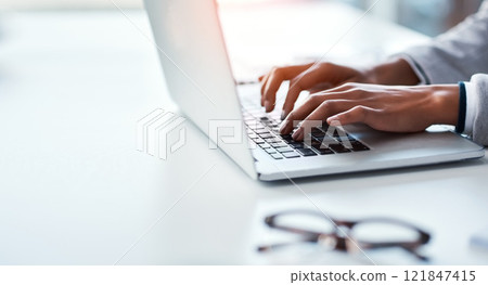 Closeup of hands of a business person typing on a laptop, replying to emails and browsing the internet while sitting at a desk in an office alone at work. Employee searching online and doing research Closeup of hands of a business person typing on a laptop, replying to emails and browsing the internet while sitting at a desk in an office alone at work. Employee searching online and doing research 121847415