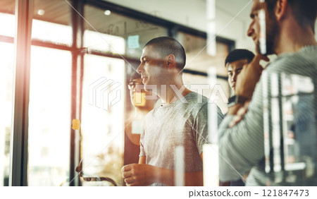 Team of employees brainstorming and planning together in a meeting using sticky notes. Group of business people thinking and finding a solution for the company strategy in an office 121847473
