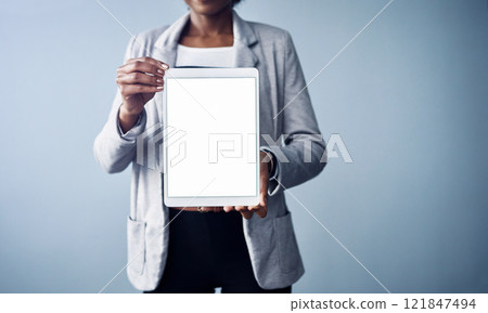Woman holding a white screen tablet looking professional mockup. Young and isolated black business corporate executive standing alone with blank digital device against a blue background copyspace 121847494
