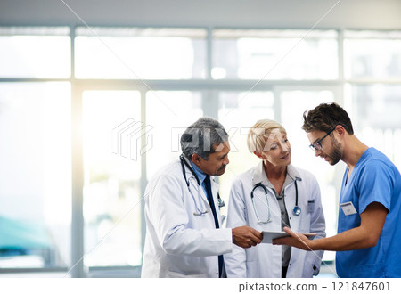 Medical professional, team and workers holding tablet, talking and solving a problem together online while standing at work in a hospital. Health experts discussing, planning and doing research Medical professional, team and workers holding tablet, talking and solving a problem together online while standing at work in a hospital. Health experts discussing, planning and doing research 121847601