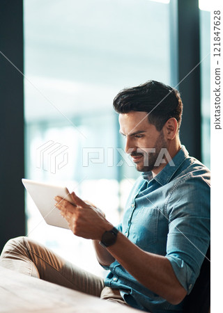 Serious businessman typing on a digital tablet in his office. Handsome male entrepreneur and executive using modern technology to communicate and network with clients using online app or via email Serious businessman typing on a digital tablet in his office. Handsome male entrepreneur and executive using modern technology to communicate and network with clients using online app or via email 121847628