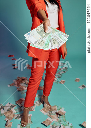 Closeup of hands holding, showing and displaying money while standing against a blue studio background alone. One stylish, trendy and fashionable female donating or giving cash in a competition 121847664