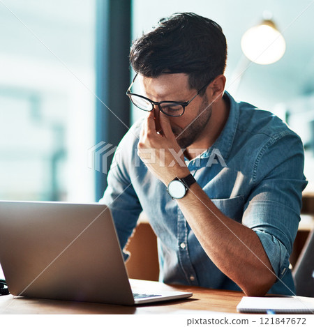 Stress, pain and eye strain from long hours working on the laptop causing headache, bad sight and vision problem. Burnout, tired and overworked young businessman removing glasses to rub dry eyes 121847672