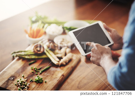 Closeup of hands of man holding a tablet to research healthy recipes, watch cooking tutorial videos and scrolling online for meal ideas while making dinner, lunch or breakfast. Man browsing on app Closeup of hands of man holding a tablet to research healthy recipes, watch cooking tutorial videos and scrolling online for meal ideas while making dinner, lunch or breakfast. Man browsing on app 121847706