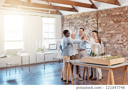 Team of happy architect engineers celebrating together with a high five after completing a small apartment complex model to scale. Group of professional designers design a blueprint office building 121847746