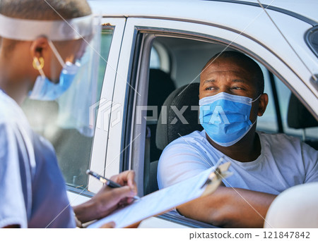 Test, questions and screening at a covid drive thru checkpoint. A man traveling in a car talking to a healthcare professional writing his coronavirus details while wearing a face mask Test, questions and screening at a covid drive thru checkpoint. A man traveling in a car talking to a healthcare professional writing his coronavirus details while wearing a face mask 121847842