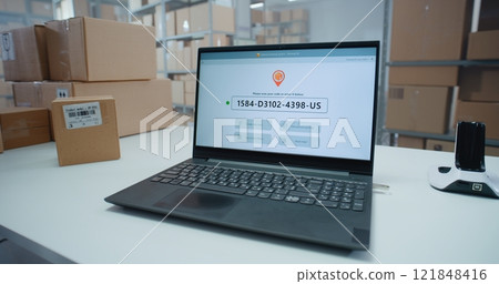 Logistics Specialist Scans Code to Check Parcel Routing on Laptop in Delivery Tracking Software 121848416