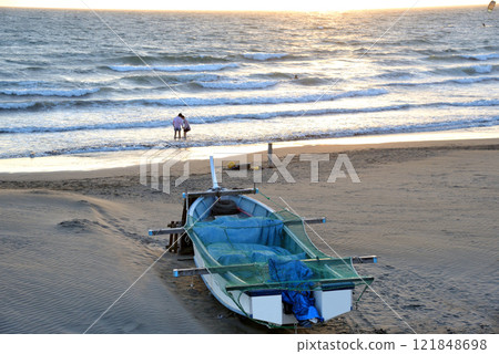 海岸上的一艘漁船和一對在岸邊玩耍的情侶 121848698