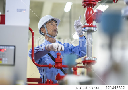 Image of a building maintenance staff member, a veteran worker, inspecting the building's sprinkler system 121848822