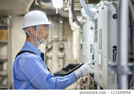 Image of a worker holding a tablet and inspecting the building's air conditioning equipment, building maintenance staff 121848956
