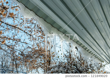 icicles on the roof of the house. dangerous ice on the corrugated board icicles on the roof of the house. dangerous ice on the corrugated board 121849020
