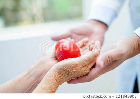 Asian elder senior woman patient holding red heart in hospital. Asian elder senior woman patient holding red heart in hospital. 121849903