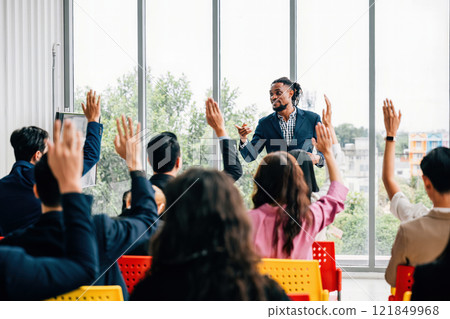 A dynamic strategy session unfolds in the boardroom as business professionals engage with questions. Hands raised signify the active participation of colleagues and employees. 121849968