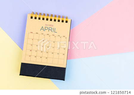 April 2025 desk calendar from brown paper on colorful background. 121850714