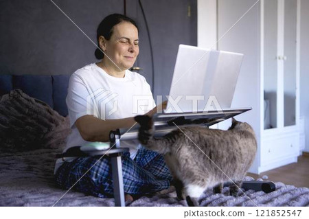 a  senior woman working from home on laptop 121852547