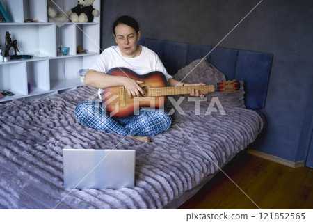 a senior woman learns to play the guitar with online lessons 121852565