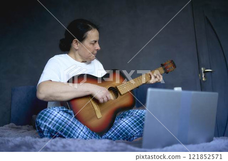 a senior woman learns to play the guitar with online lessons a senior woman learns to play the guitar with online lessons 121852571