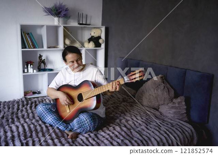 a senior woman learns to play the guitar with online lessons a senior woman learns to play the guitar with online lessons 121852574