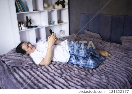 a senior woman chatting on the phone in bed 121852577