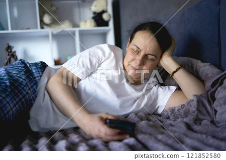 a senior woman chatting on the phone in bed 121852580