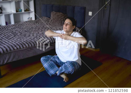 a senior woman performs somatic exercises, yoga at home a senior woman performs somatic exercises, yoga at home 121852598