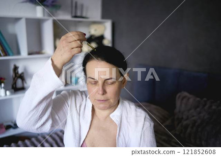 a senior woman uses a product for hair growth 121852608