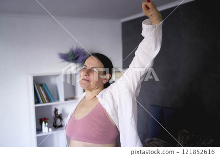 a senior woman in underwear stretching, resting, enjoying life on bed at home 121852616