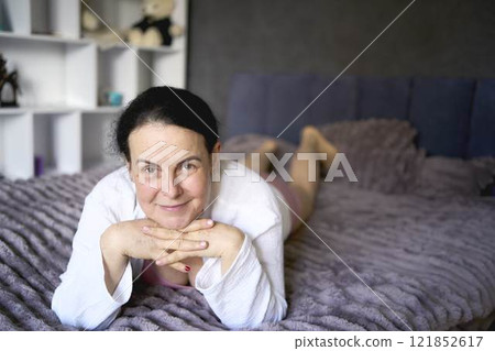 a senior woman in underwear stretching, resting, enjoying life on bed at home a senior woman in underwear stretching, resting, enjoying life on bed at home 121852617