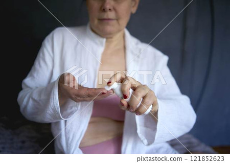 a senior woman in underwear on the bed performs routine self-care with face and body cosmetics, face foam a senior woman in underwear on the bed performs routine self-care with face and body cosmetics, face foam 121852623
