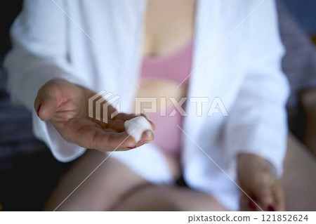 a       senior woman in underwear on the bed performs routine self-care with face and body cosmetics, face foam 121852624