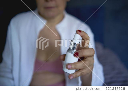 a senior woman in underwear on the bed performs routine self-care with face and body cosmetics , Face Mist, tonic a senior woman in underwear on the bed performs routine self-care with face and body cosmetics , Face Mist, tonic 121852626