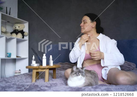 a senior woman in underwear on the bed performs routine self-care with face and body cosmetics a senior woman in underwear on the bed performs routine self-care with face and body cosmetics 121852668