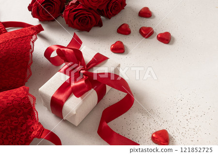 Valentine's day romantic sensual concept. Red lace lingerie, bustier underwear, candy sweets and red roses on white background. Close up. Romantic date. Valentine's day romantic sensual concept. Red lace lingerie, bustier underwear, candy sweets and red roses on white background. Close up. Romantic date. 121852725