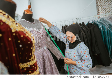 A talented seamstress is expertly tailoring an elegant traditional dress in her workshop 121852735