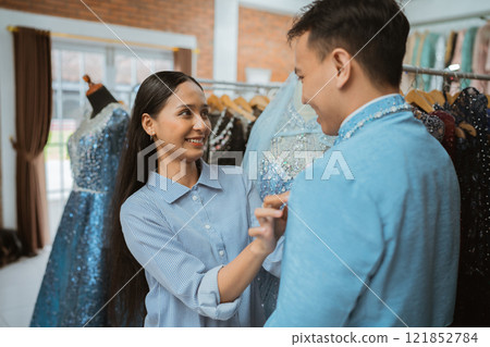 A couple shops for elegant dresses at a boutique, enjoying the experience together 121852784