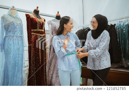 Two talented women are excitedly preparing for a fashion show in a boutique 121852785