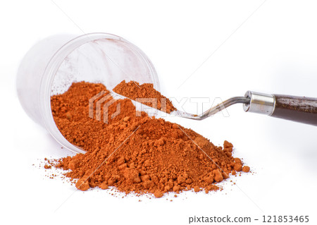 Bright Orange pigment Spice Spilling From Container With Scoop on White Background 121853465