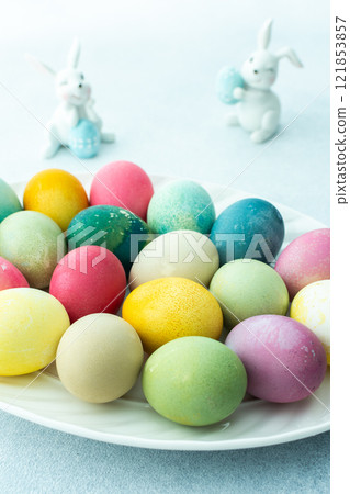 Multi-colored Easter eggs in an oval dish on a blue background, Happy Easter holiday 121853857