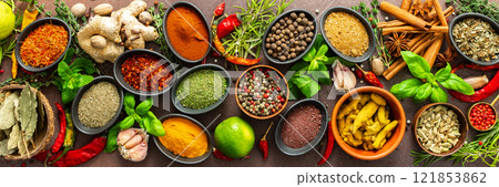 A rich palette of colorful spices and herbs, resting on a brown background, radiating freshness and an inviting aroma, perfect for gourmet inspiration, banner 121853862