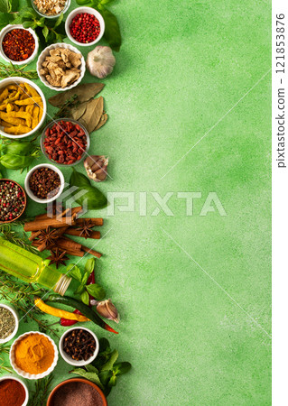 Fresh, fragrant spices and herbs arranged in an array of colors, sitting on a soft green backdrop, bringing flavor and zest to any kitchen, top view and copy space 121853876