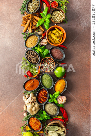 An artistic display of fragrant herbs and spices, scattered on a brown surface, blending natural hues and rich textures for a rustic culinary charm 121853877