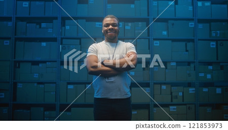 African American Logistics Specialist Crossing Arms, Smiling and Looking at Camera in Sorting Center African American Logistics Specialist Crossing Arms, Smiling and Looking at Camera in Sorting Center 121853973