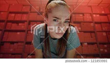 Serious Female Logistics Specialist in Uniform Looking at Camera in Warehouse Facility Serious Female Logistics Specialist in Uniform Looking at Camera in Warehouse Facility 121853991