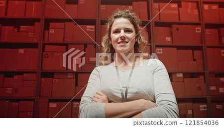 Female Warehouse Worker Standing with Crossing Arms, Smiling, Looking at Camera 121854036