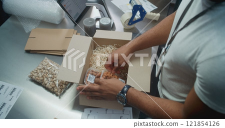 Top View on African American Shipping and Receiving Clerk Packing Parcel with Food Top View on African American Shipping and Receiving Clerk Packing Parcel with Food 121854126