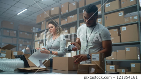 Multiethnic Warehouse Workers Packing Cardboard Parcels with Online Orders 121854161