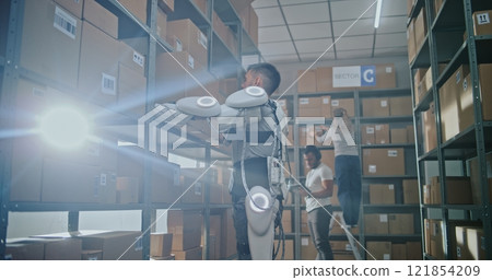 Advanced Warehouse: Worker Wearing Powered Exoskeleton Places Parcel on Shelf 121854209