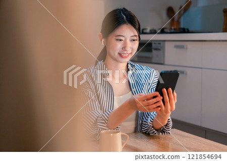 一位獨居女性晚上喜歡在智慧型手機上瀏覽內容 一位獨居女性晚上喜歡在智慧型手機上瀏覽內容 121854694