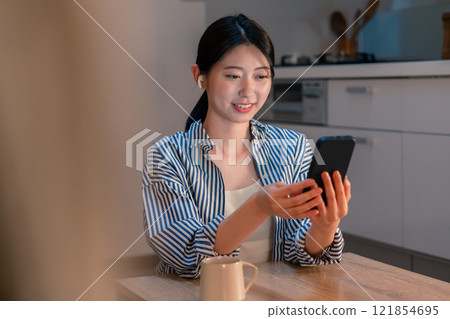 A woman living alone enjoying content on her smartphone at night A woman living alone enjoying content on her smartphone at night 121854695