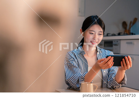 一位獨居女性晚上喜歡在智慧型手機上瀏覽內容 一位獨居女性晚上喜歡在智慧型手機上瀏覽內容 121854710